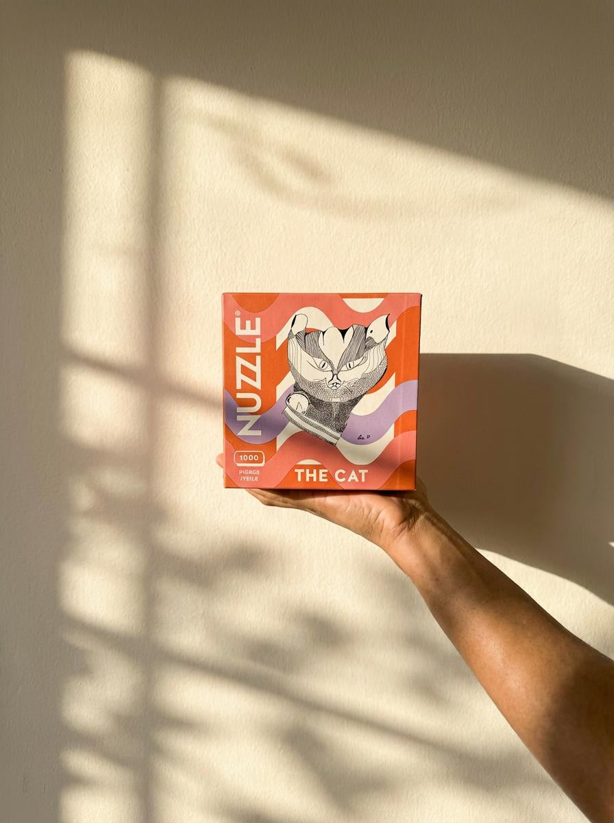 Hand holding a NUZZLE product box labeled against an off-white wall